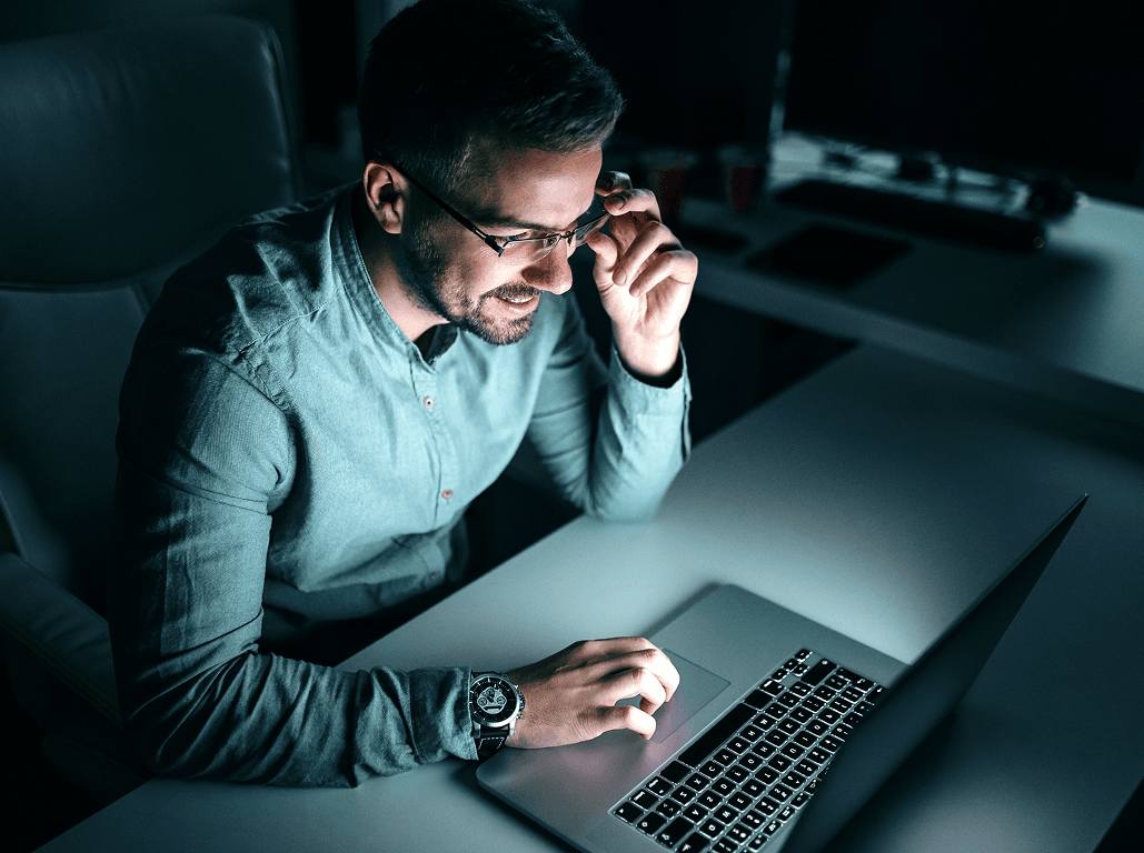 Professional reviewing a laptop in a low-lit workspace